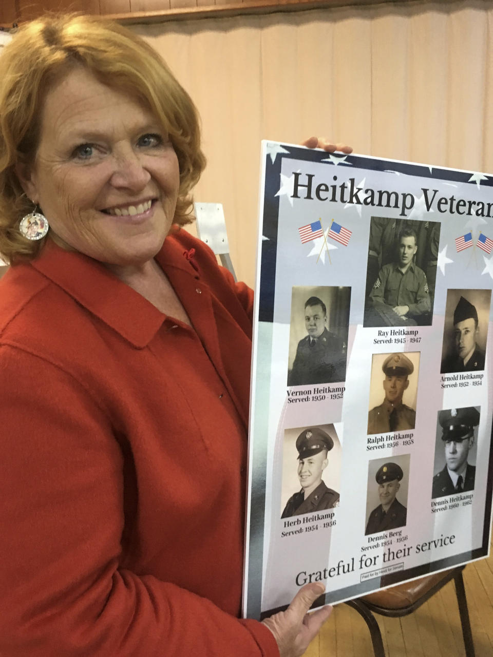 North Dakota Democratic Sen. Heidi Heitkamp holds up a poster of her relatives who have served in the military on Tuesday, Oct. 23, 2018 in Bismarck, North Dakota. Former Defense Secretary Chuck Hagel is campaigning across the state for Heitkamp, who is viewed as one of the most vulnerable candidates among red-state Democrats in the Senate. (AP Photo/James MacPherson)