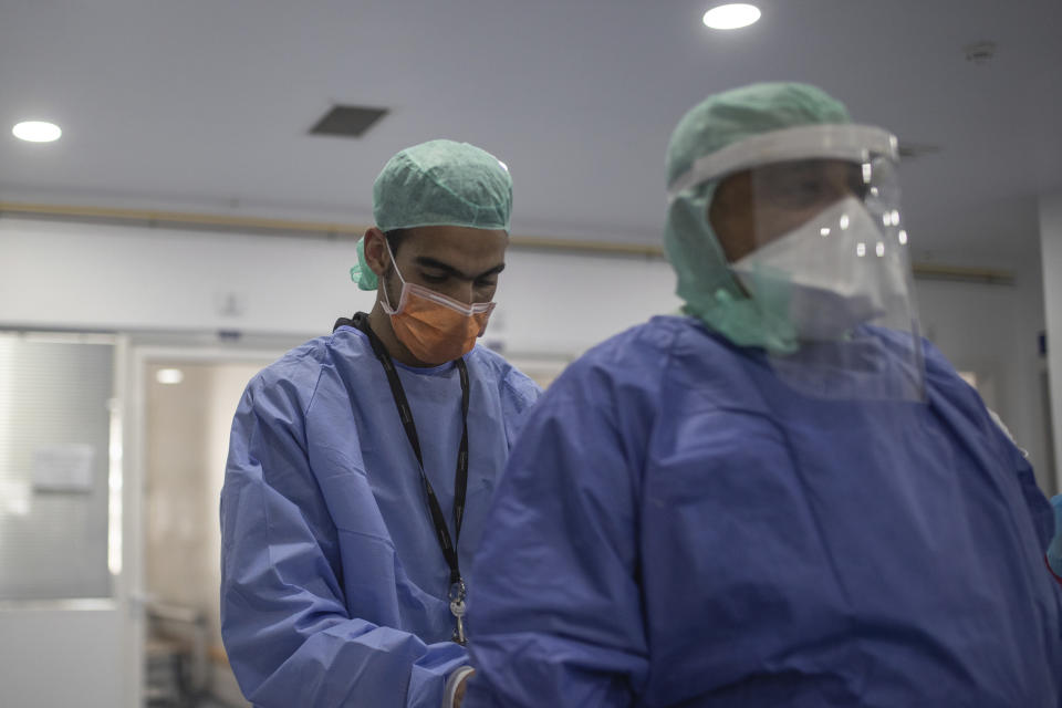 In this photo taken on Wednesday, April 15, 2020, healthcare workers assist each other inside one of the COVID-19 intensive care units (ICU) of the Moulay Abdellah hospital in Sale, Morocco. Coronavirus has upended life for Morocco's medical workers. They enjoy better medical facilities than in much of Africa but are often short of the equipment available in European hospitals, which also found themselves overwhelmed. (AP Photo/Mosa'ab Elshamy)
