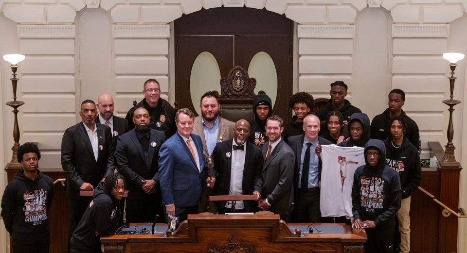 North High School basketball coach Al Pettway, center, is flanked by State Sen. Michael Moore, left, State Rep. Dan Donahue, and State Sen. Peter Durant, right, along with players and staff as the two-time state champions are honored in the Senate Chambers during a visit to the Massachusetts State House in Boston Thursday.