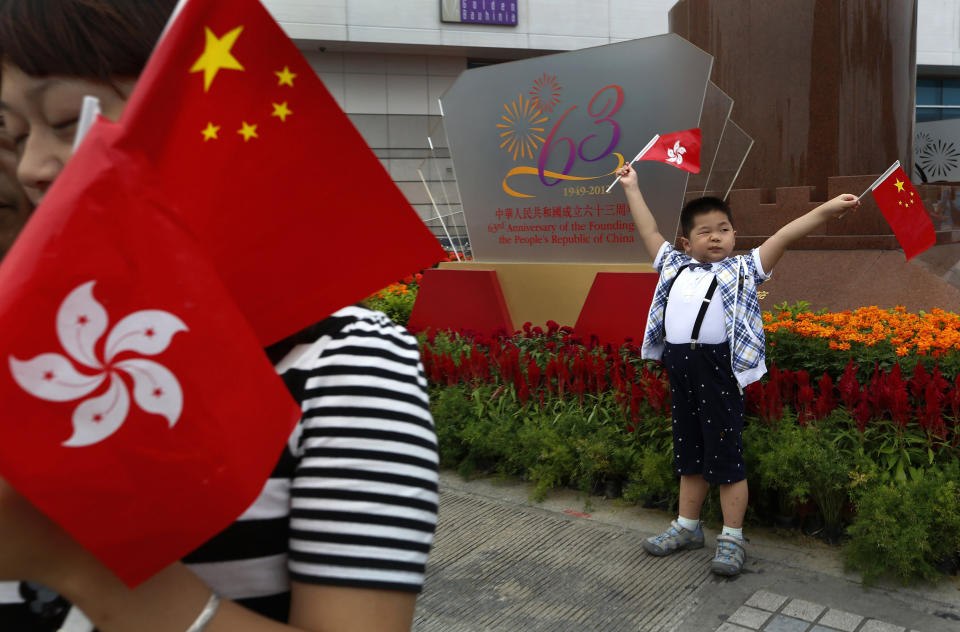 FILE - In this Monday, Oct. 1, 2012, file photo, a children from mainland China holding flags of China and Hong Kong poses at the venue of the flag-raising ceremony for China's National Day in Hong Kong. A year after Beijing imposed a harsh national security law on Hong Kong, the civil liberties that raised hopes for more democracy are fading.(AP Photo/Vincent Yu, File)