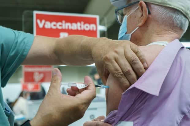 Seniors receive their COVID-19 vaccine at a clinic at Olympic Stadium. The mass vaccination campaign will move to Quebec's regions later this month.  (Paul Chiasson/The Canadian Press - image credit)