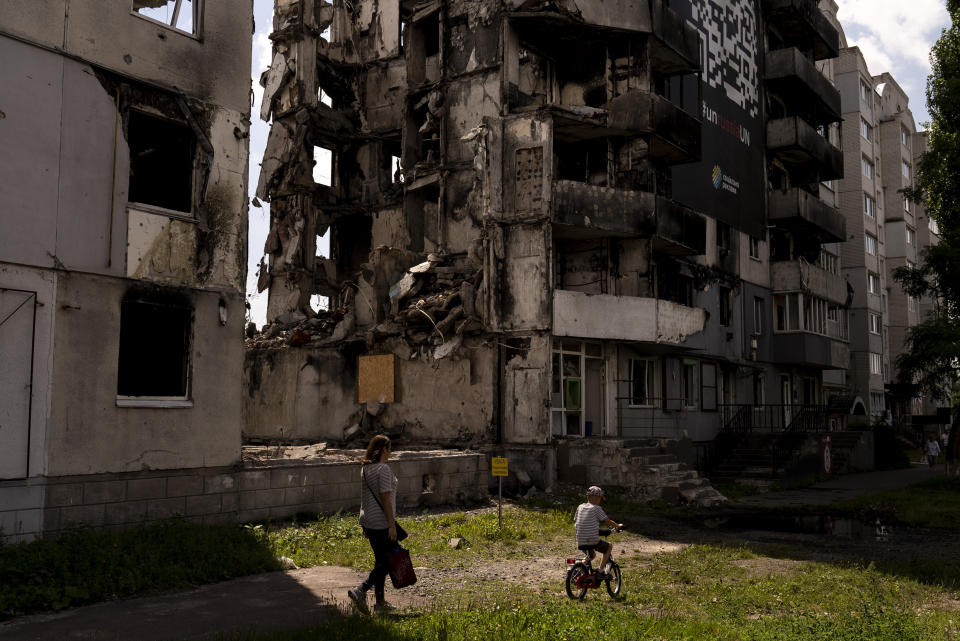 A woman and a boy make their way past an apartment building destroyed in Russian attacks in Borodyanka, Ukraine, Wednesday, Aug. 2, 2023. Borodyanka was occupied by Russian troops at the beginning of their full-scale invasion last year. (AP Photo/Jae C. Hong)