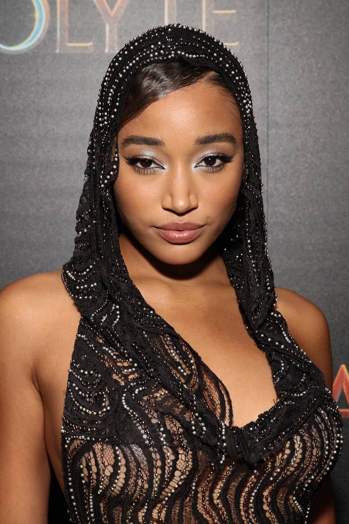 Amandla Stenberg attends an event wearing a beaded, hooded dress with an intricate, sheer design