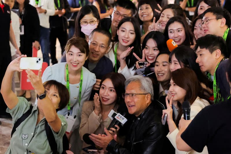 FILE PHOTO: Nvidia CEO Jensen Huang poses for selfie with members of the media at COMPUTEX forum in Taipei