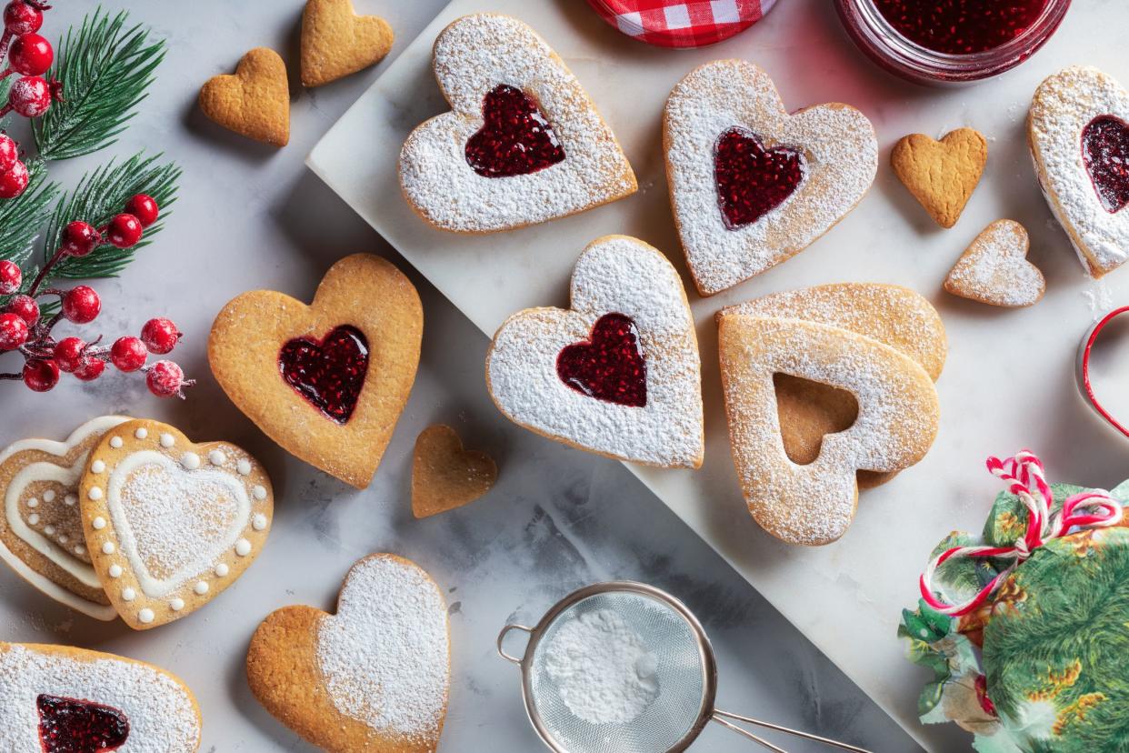 Top view of traditional Linzer cookies with raspberry jam heart on table. Christmas or Valentines day traditional homemade heart shaped cookies, tasty snack.