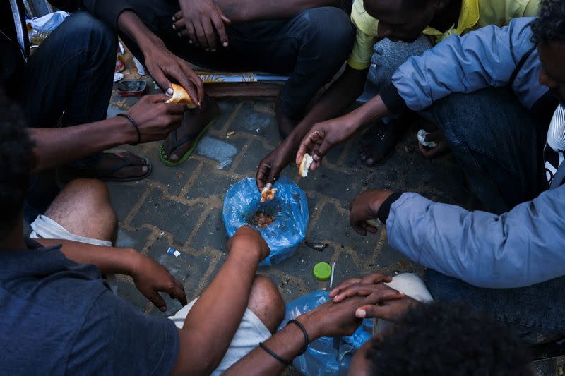 Migrants share food as they wait outside the United Nations High Commissioner for Refugees (UNHCR) negotiation office in Tripoli