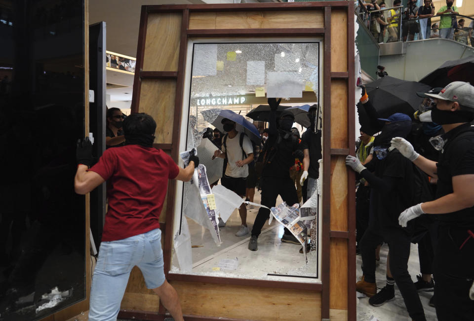 Protesters damage an advertisement board in Hong Kong on Sunday, Sept. 22, 2019. Protesters in Hong Kong trampled a Chinese flag, vandalized a subway station and lit a fire across a wide street on Sunday, as pro-democracy demonstrations took a violent turn once again. (AP Photo/Vincent Yu)