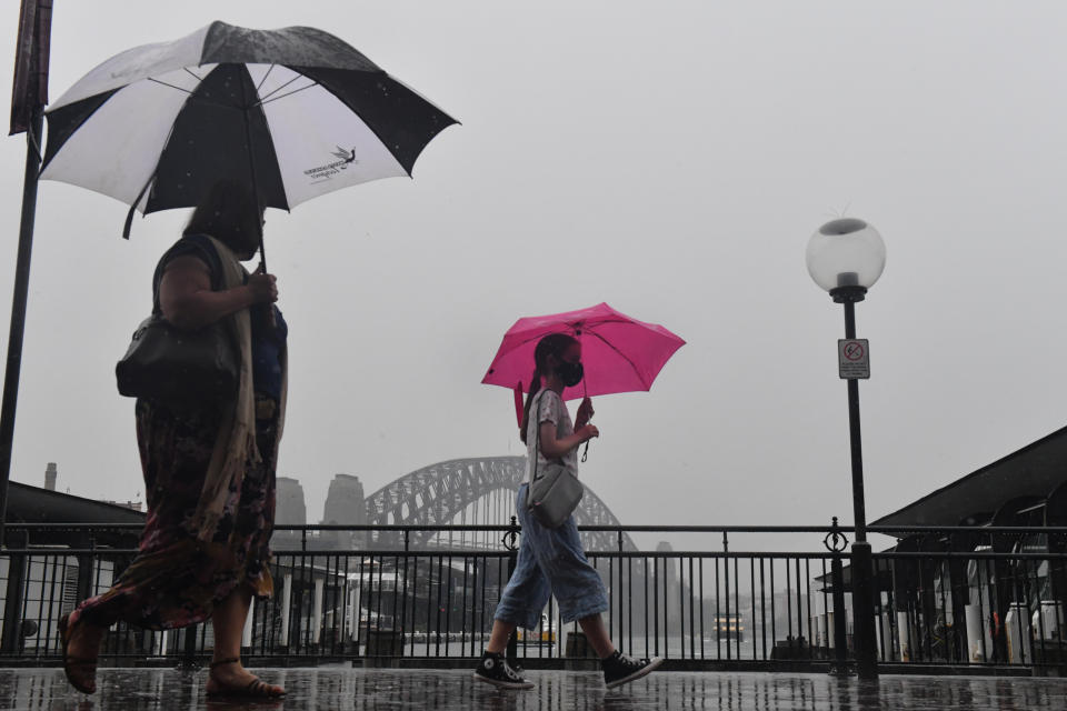 Pedestrians walk past the Sydney Harbour Bridge during wet weather in Sydney, Wednesday, November 10, 2021. 