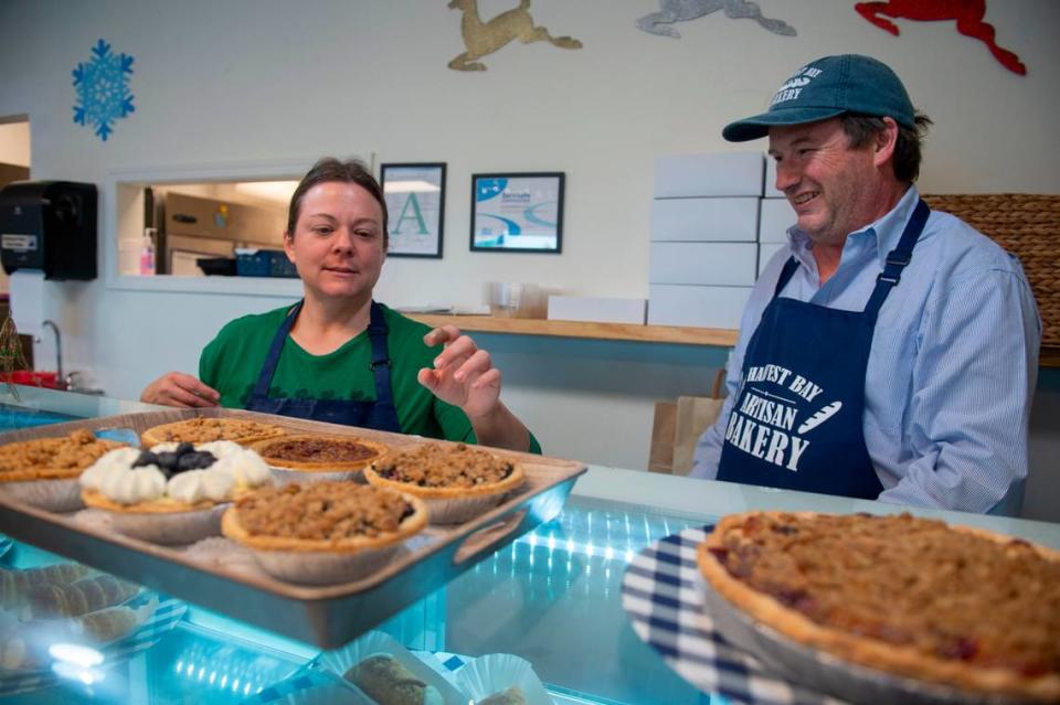 Owner Alex Lacy and baker Brooke Craig show off different pies for sale at Harvest Bay Artisan Bakery in Bay St. Louis on Thursday, Dec. 7, 2023.