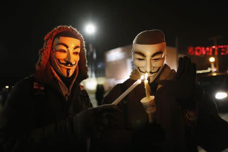 Protesters wearing Guy Fawkes masks take part in a candlelight vigil outside the Ferguson Police Department in Ferguson, Missouri, November 21, 2014. REUTERS/Jim Young