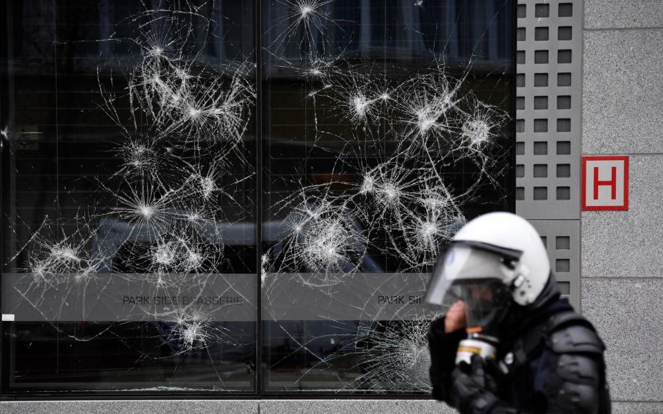 A police officer walks by a damaged building in the European Union quarter - AP