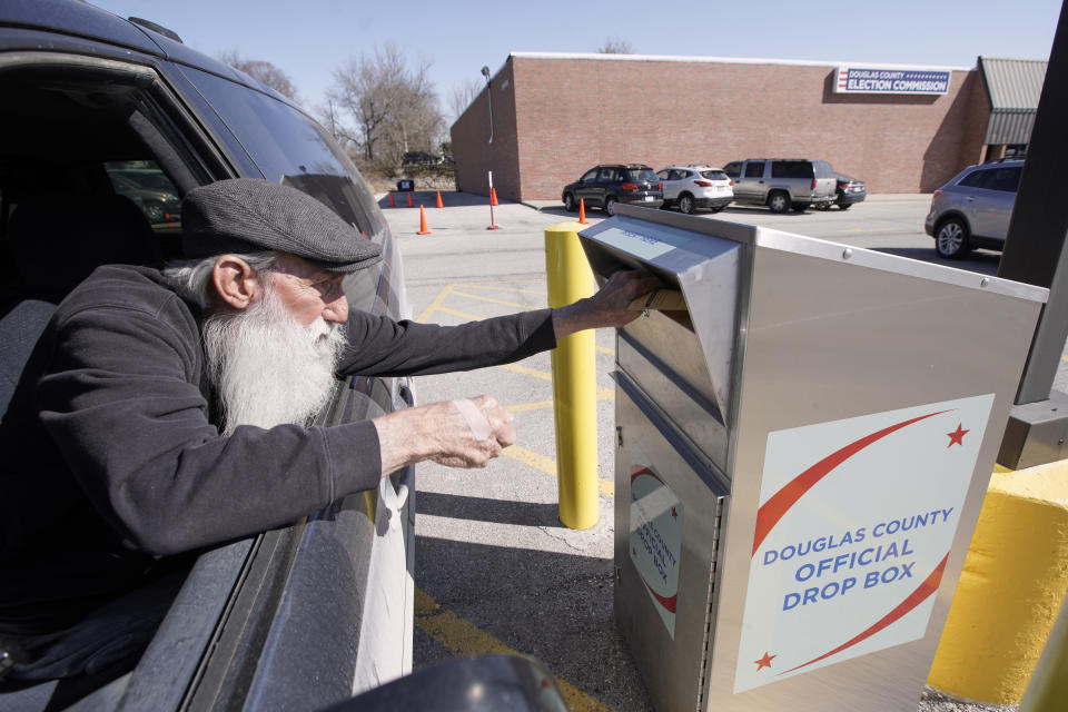 In this April 10, 2020 photo, Robert E. Lee inserts his ballot into a drop box outside the Douglas County Election Commission office in Omaha, Neb. Officials in Nebraska are forging ahead with plans for the state’s May 12 primary despite calls from Democrats to only offer voting by mail and concerns from public health officials that in-person voting will help the coronavirus spread. Republican leaders have encouraged people to request absentee ballots but say polling places will be open. (AP Photo/Nati Harnik)