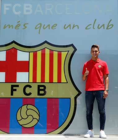 Soccer player Denis Suarez poses next to a FC Barcelona's giant logo at their offices in Barcelona, Spain, July 5, 2016. REUTERS/Albert Gea