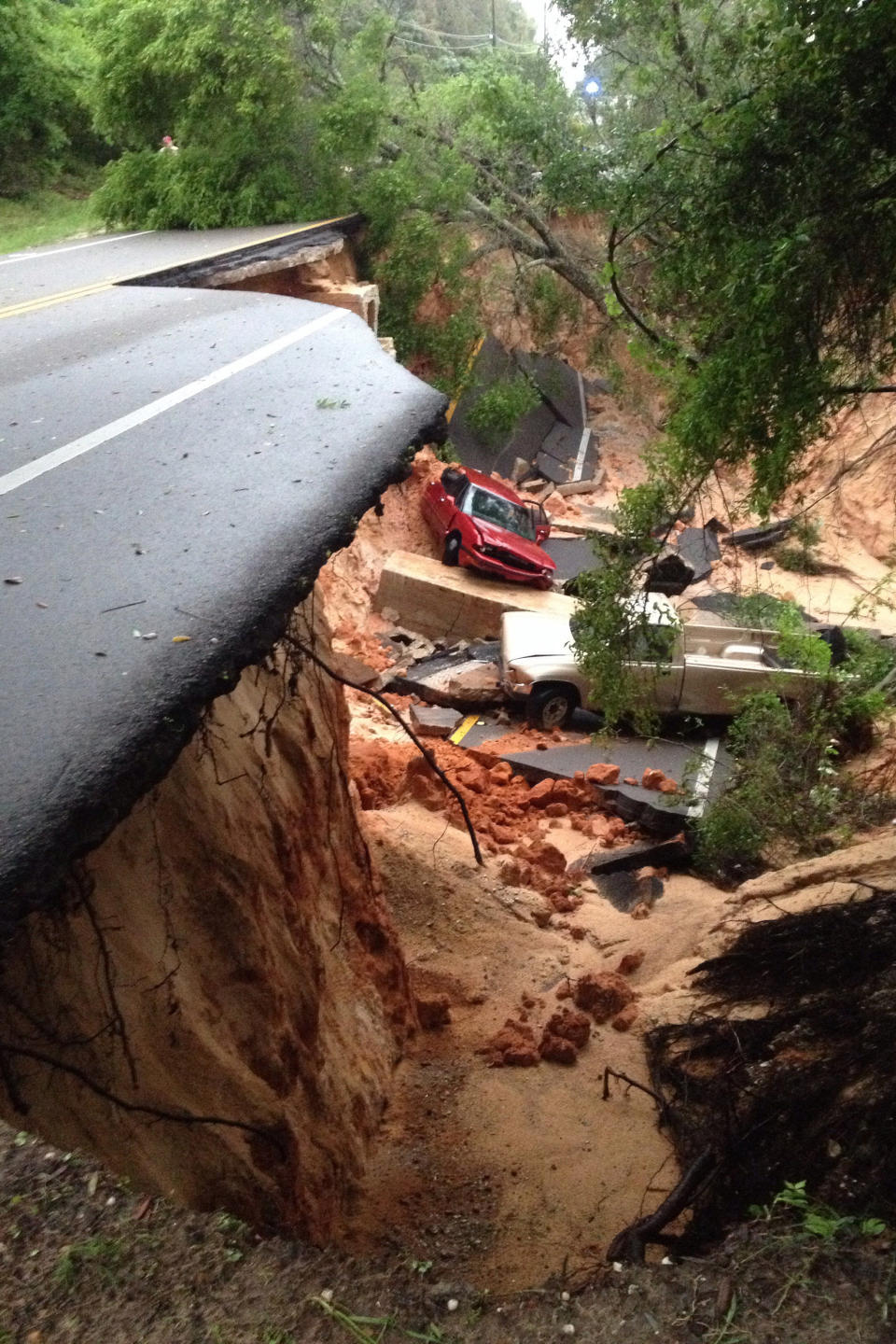 A car lies at the bottom of a ravine after the Scenic Highway collapsed near Pensacola, Fla., Wednesday April 30, 2014. Heavy rains and flooding have left people stranded in houses and cars in the Florida Panhandle and along the Alabama coast. (AP Photo/Pensacola News Journal, Katie E. King)