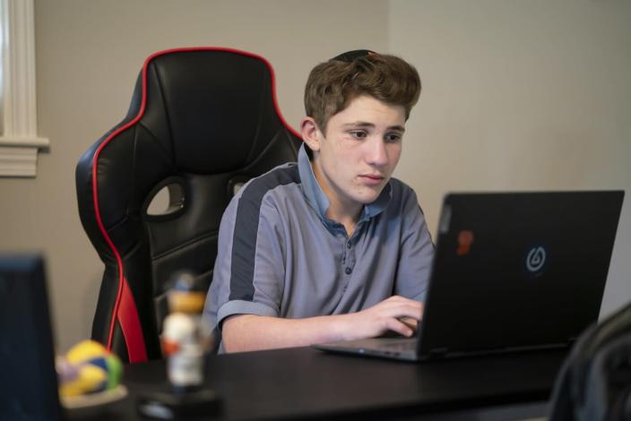 A teenage boy works on a computer.