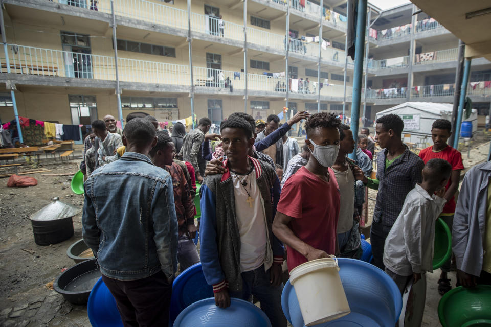 Displaced Tigrayans queue to receive food at the Hadnet General Secondary School which has become a makeshift home to thousands displaced by the conflict, in Mekele, in the Tigray region of northern Ethiopia Wednesday, May 5, 2021. The Tigray conflict has displaced more than 1 million people, the International Organization for Migration reported in April, and the numbers continue to rise. (AP Photo/Ben Curtis)