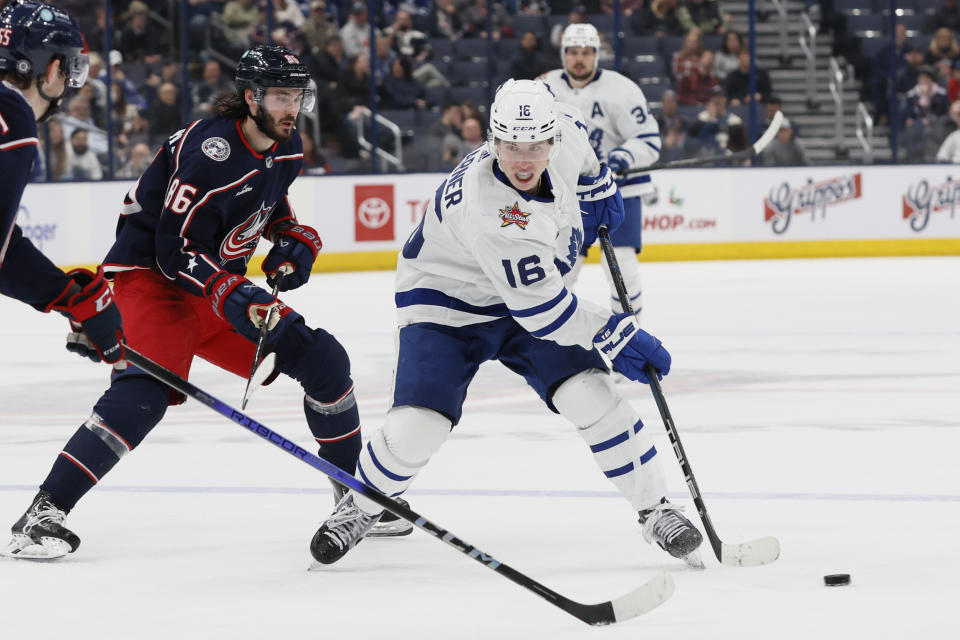 Toronto Maple Leafs' Mitchell Marner, right, looks for an open pass as Columbus Blue Jackets' Kirill Marchenko (86) defends during the third period of an NHL hockey game Saturday, Dec. 23, 2023, in Columbus, Ohio. (AP Photo/Jay LaPrete)