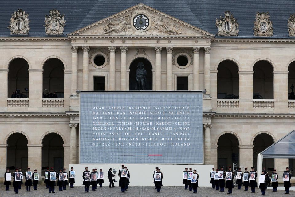 Republican Guards hold portraits of the French victims of the Oct.7 2023 Hamas' attack, during a ceremony at the Invalides monument, Wednesday, Feb.7, 2024. France is paying tribute to French victims of Hamas' Oct. 7 attack, in a national ceremony led by President Emmanuel Macron four months after the deadly assault in Israel that killed some 1,200 people, mostly civilians, and saw around 250 abducted.(Gonzalo Fuentes/Pool via AP)