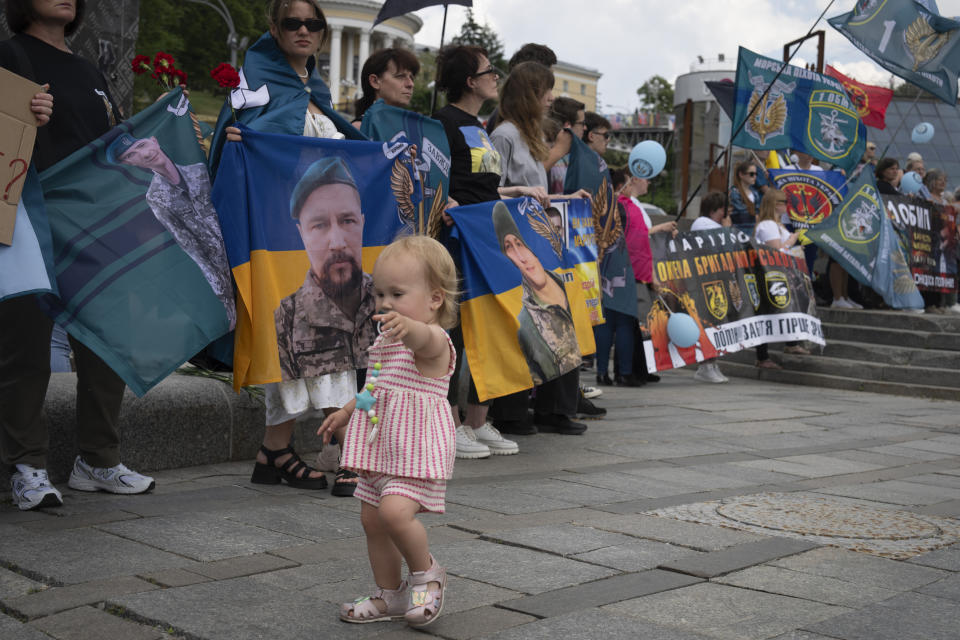 A POW's child runs past activists during a rally demanding the release of Ukrainian soldiers who were captured by Russia during the war, in the Independence square in Kyiv, Ukraine, Thursday, May 23, 2024. (AP Photo/Efrem Lukatsky)