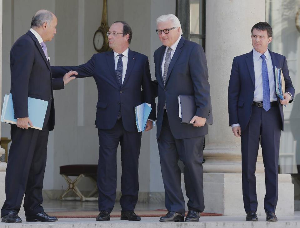 French President Francois Hollande, second left, talks to French foreign minister Laurent Fabius, left, and German Foreign Minister Frank-Walter Steinmeier, rigth, at the end of the weekly Cabinet meeting in the Elysee Palace in Paris. Wednesday, May 14, 2014. At right French Prime Minister Manuel Valls looks on. (AP Photo/Jacques Brinon)