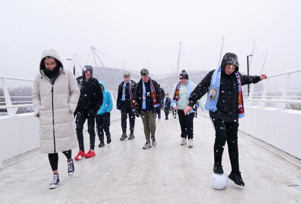 Fans cross the bridge to the Etihad Stadium in the snow before Manchester City’s game with West Ham (Martin Rickett/PA) (PA Wire)