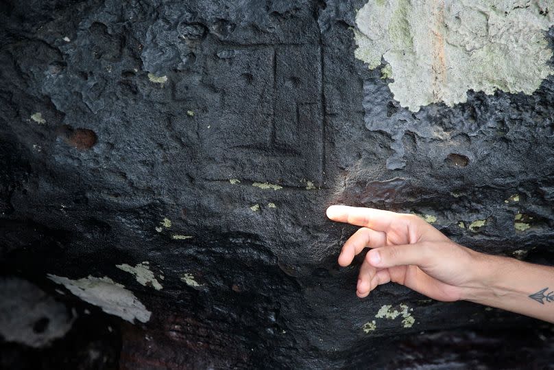 Archaeologist Jaime de Santana Oliveira points to an ancient stone carving, exposed after water levels dropped to record lows during drought in Manaus, 23 October.