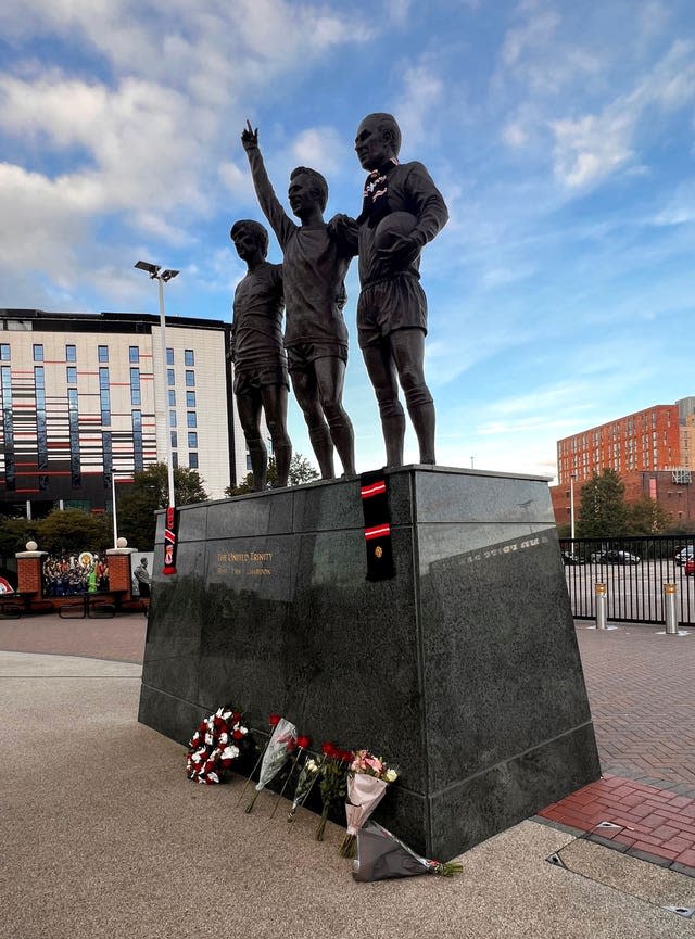 Tributes are laid in memory of Sir Bobby Charlton by The United Trinity statue at Old Trafford