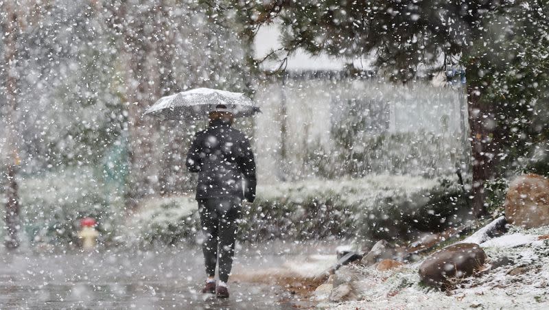 A pedestrian walks through a neighborhood through the snowstorm in Cottonwood Heights on Thursday, Oct. 26, 2023.