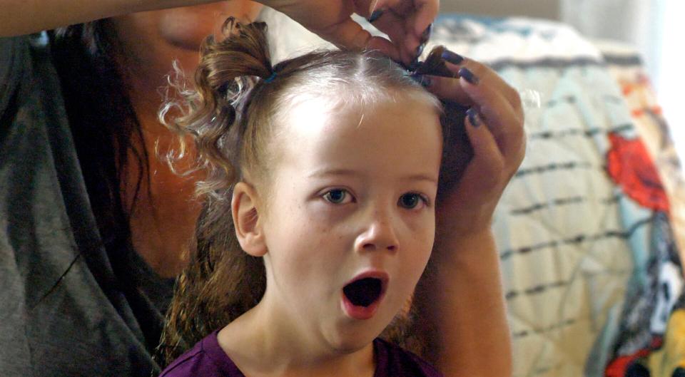 In this May 6, 2019, photo, Amie Schofield, rear, does her daughter Victory hair at their home in Ogden, Utah. Victory has XXY chromosomes. Amie and her husband decided to raise Victory without pushing either gender. There would be no surgery. At 18 months, Victory began gravitating toward dresses and bows, and loudly insisting on wearing her hair long.