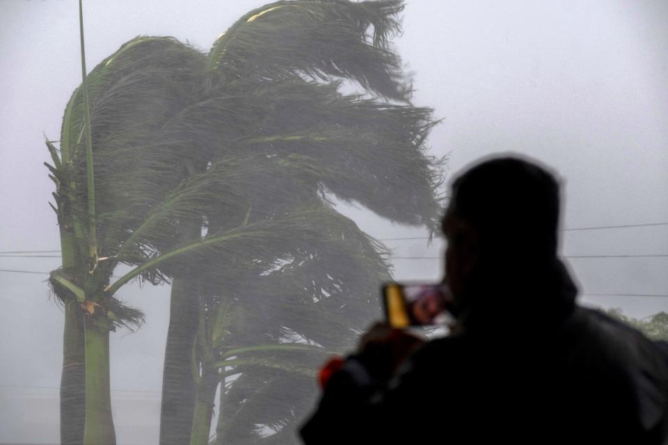 TOPSHOT - A man live streams as gusts from Hurricane Ian hits in Punta Gorda, Florida on September 28, 2022. - Hurricane Ian slammed into Florida September 28, 2022, with the National Hurricane Center saying the eye of the storm made landfall at 1905 GMT as high winds and heavy rain pounded the coast. (Photo by Ricardo ARDUENGO / AFP) (Photo by RICARDO ARDUENGO/AFP via Getty Images)