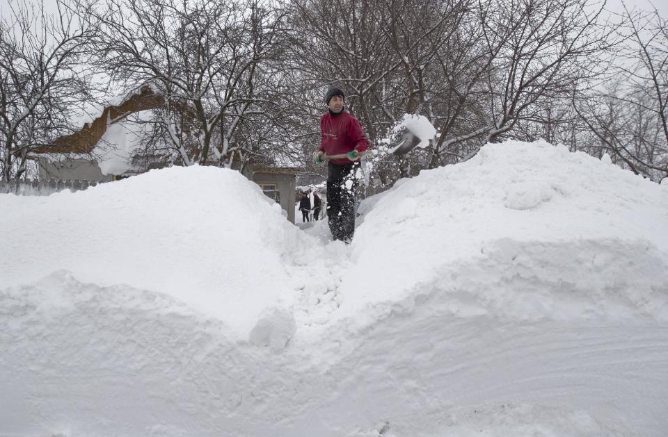 CORRECTS TO MAN A man shovels snow to clear the entrance to his home in the village of Smeeni, Romania, Tuesday, Jan. 28, 2014. Snow storms are forecast for the coming days in the already affected southeastern regions of Romania in which road and rail traffic were badly disrupted. (AP Photo/Vadim Ghirda)