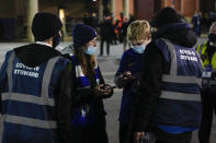 Stewards check the fans for their COVID-19 pass on the smartphone prior to the start of the English Premier League soccer match between Chelsea and Everton, at the Stamford Bridge stadium in London, Thursday, Dec.16, 2021. (AP Photo/Alastair Grant)