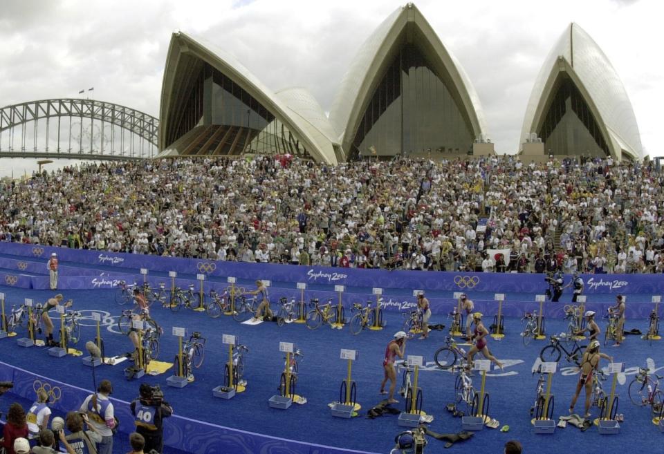 Athletes transition from swimming to bicycling in front of the Sydney Opera House for the second leg of the women's triathlon at the 2000 Summer Olympic Games in Sydney, Saturday, Sept. 16, 2000. Men's world champion Tamirat Tola of Ethiopia and 2022 Paris Marathon women's champion Judith Jeptum Korir of Kenya will headline the fields for the Sydney Marathon in September 2023. (AP Photo/Rick Rycroft, File)