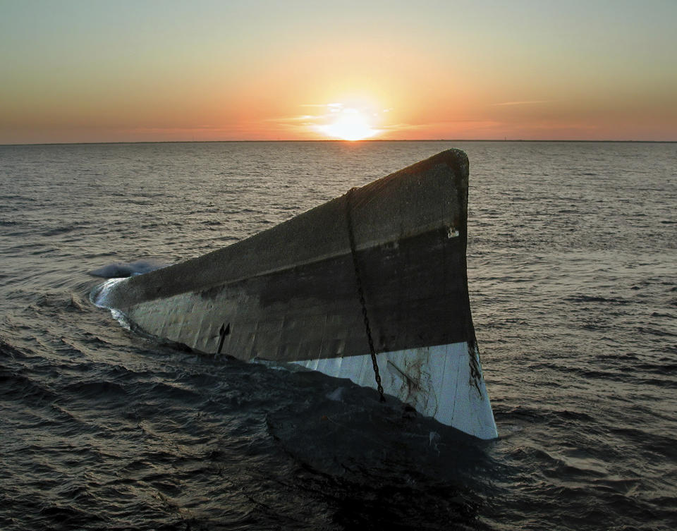 FILE - In this photo provided by the Florida Keys News Bureau, the sun sets over the upside-down hull of the Spiegel Grove. The 510-foot-long retired Naval Landing Ship Dock was to be scuttled upright to create an artificial reef off the Florida Keys, but sank prematurely May 17, 2002, and rolled over. The vessel was eventually fully sunk. The Spiegel Grove's storied past is to be celebrated May 17, 2022, the 20th anniversary of the sinking, with an event at a local cultural center that features key individuals reminiscing about the project. (Andy Newman/Florida Keys News Bureau via AP, File)