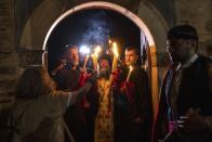 Orthodox Archimandrite Rafael delivers the Holy Fire brought from Jerusalem, at the church of Agioi Anargyroi, in Athens, Greece, on Saturday, April 23, 2022. For the first time in three years, Greeks were able to celebrate Easter without the restrictions made necessary by the coronavirus pandemic. (AP Photo/Yorgos Karahalis)