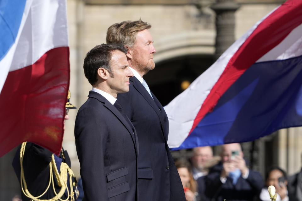 French President Emmanuel Macron, left, and Dutch King Willem-Alexander listen to national anthems outside the royal palace on Dam square in Amsterdam, Netherlands, Tuesday, April 11, 2023. French President Emmanuel Macron begins a two-day state visit to the Netherlands on Tuesday and is making a speech on his vision for the future of Europe. (AP Photo/Peter Dejong)