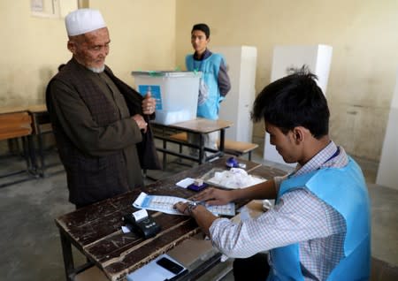 An election official checks voter's documents at a polling station in Kabul