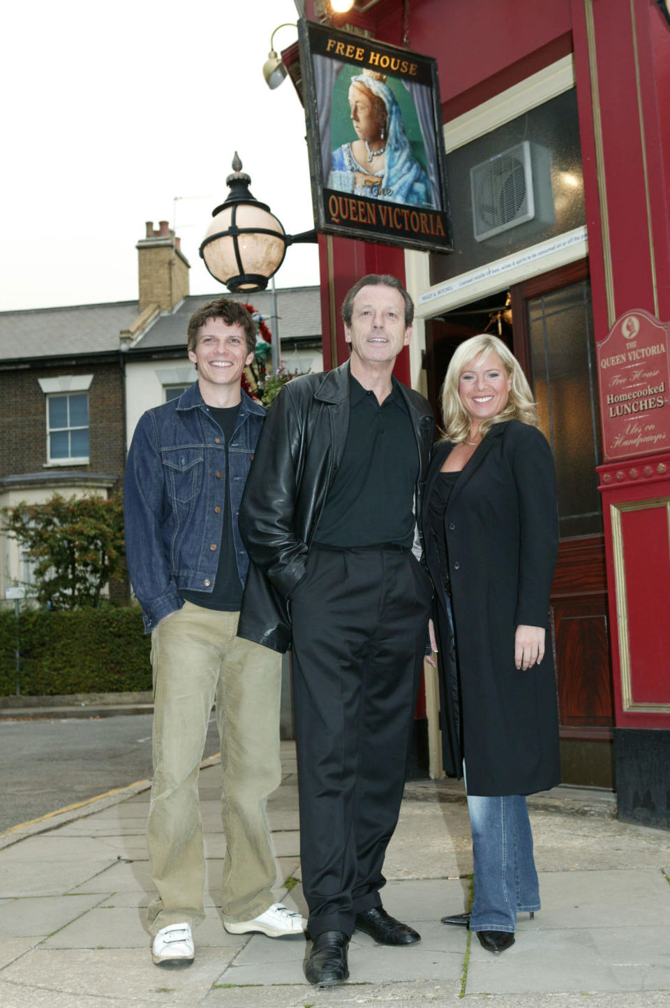 Leslie Grantham (C), Nigel Harman (L) and actress Letitia Dean pose outside the Queen Vic pub on the Eastenders set to promote their new storyline featuring the return of Dirty Den, at Elstree Studios on September 28, 2003 in London.  (Photo by Rod Johnson/Getty Images)