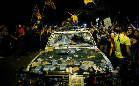 A police car destroyed during protests over the arrest of Catalan officials  - Credit: Reuters