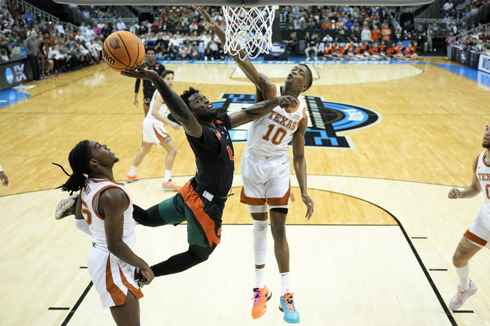 Miami guard Bensley Joseph drives to the basket past Texas guard Sir'Jabari Rice and guard Marcus Carr, left, in the first half of an Elite 8 college basketball game in the Midwest Regional of the NCAA Tournament Sunday, March 26, 2023, in Kansas City, Mo. (AP Photo/Jeff Roberson)