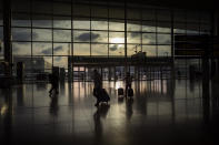 Passengers walk in an empty terminal at the airport of Barcelona, Spain, Thursday, March 19, 2020. For most people, the new coronavirus causes only mild or moderate symptoms. For some, it can cause more severe illness, especially in older adults and people with existing health problems. (AP Photo/Emilio Morenatti)