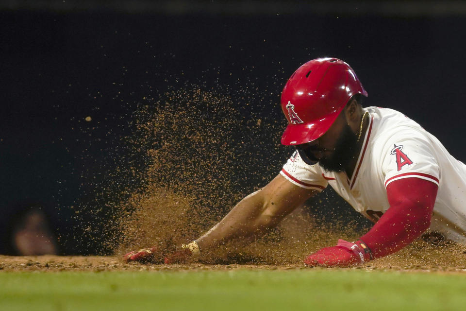Los Angeles Angels' Luis Rengifo, left, slides past Baltimore Orioles catcher Adley Rutschman to score off a double hit by Zach Neto during the fourth inning of a baseball game, Tuesday, April 23, 2024, in Anaheim, Calif. (AP Photo/Ryan Sun)