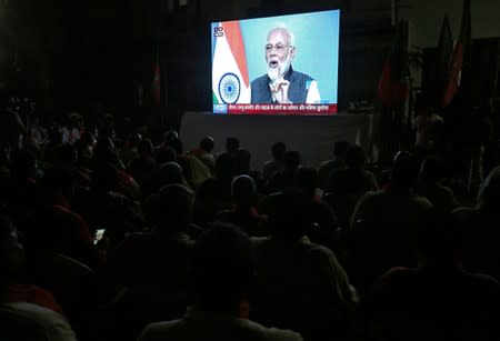 People watch as Prime Minister Narendra Modi delivers an address to the nation, on a TV screen in Ahmedabad