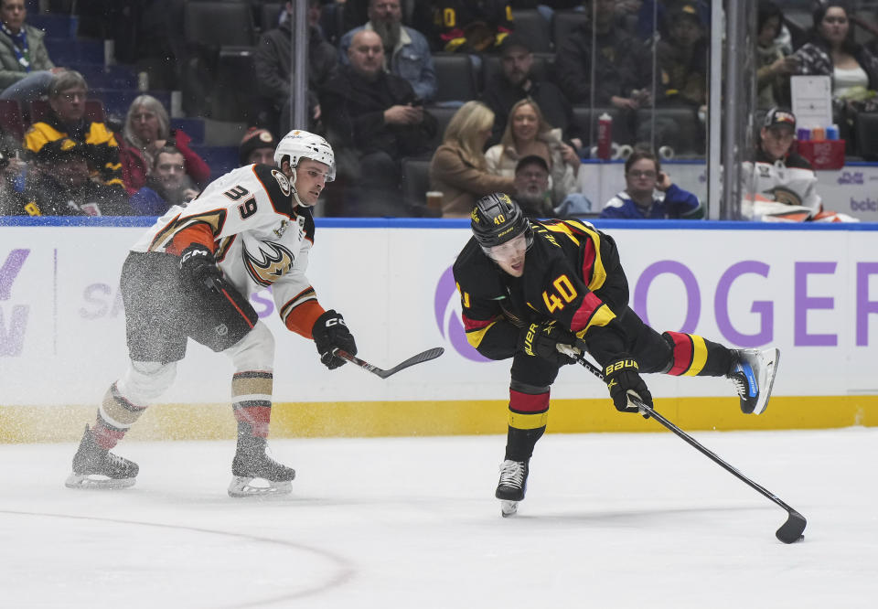 Vancouver Canucks' Elias Pettersson (40) reaches for the puck after being checked by Anaheim Ducks' Sam Carrick (39) during the third period of an NHL hockey game in Vancouver, on Tuesday, Nov. 28, 2023. (Darryl Dyck/The Canadian Press via AP)