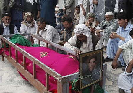 Shi'ite Muslim men from the ethnic Hazara minority sit as they mourn beside the coffin of their relative who was killed after gunmen opened fire on a bus during a funeral ceremony in Quetta October 23, 2014. REUTERS/Naseer Ahmed