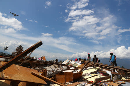 Villagers search for their belongings as a commercial aircraft is about to land in an area after an earthquake hit Petobo neighbourhood in Palu, Indonesia, October 6, 2018. REUTERS/Athit Perawongmetha