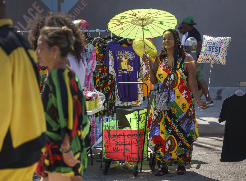 Bridgette Brisco sells dresses, umbrellas and hats during Juneteenth celebrations at Leimert Park in Los Angeles Saturday, June 18, 2022. (AP Photo/Damian Dovarganes)