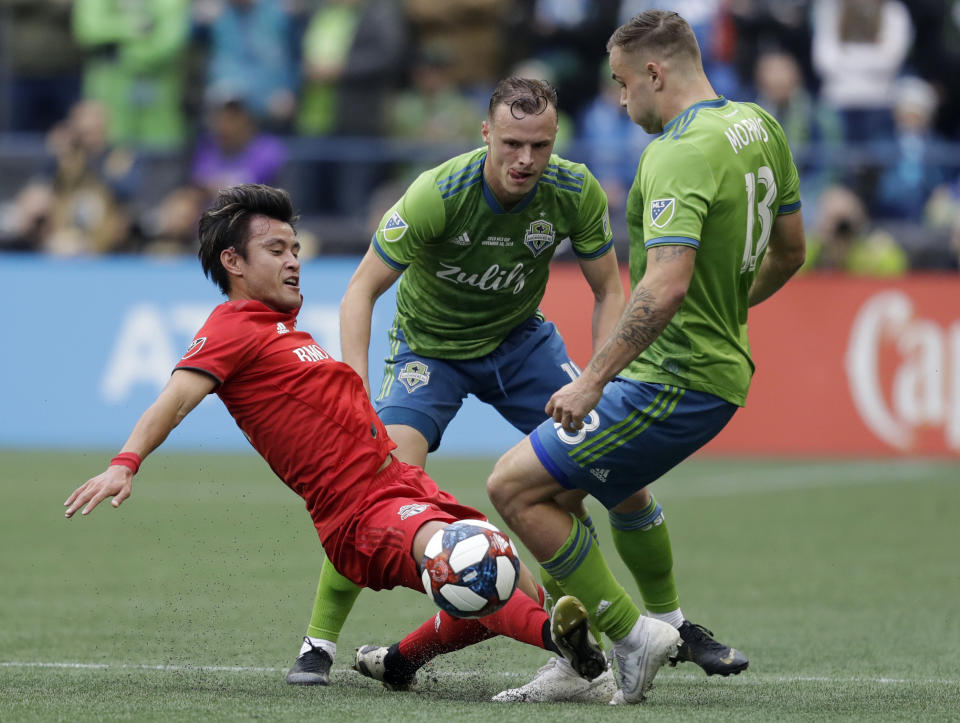 Toronto FC's Tsubasa Endoh, left, battles for a ball with Seattle Sounders' Jordan Morris, right, Sunday, Nov. 10, 2019, during the first half of the MLS Cup championship soccer match in Seattle. (AP Photo/Elaine Thompson)