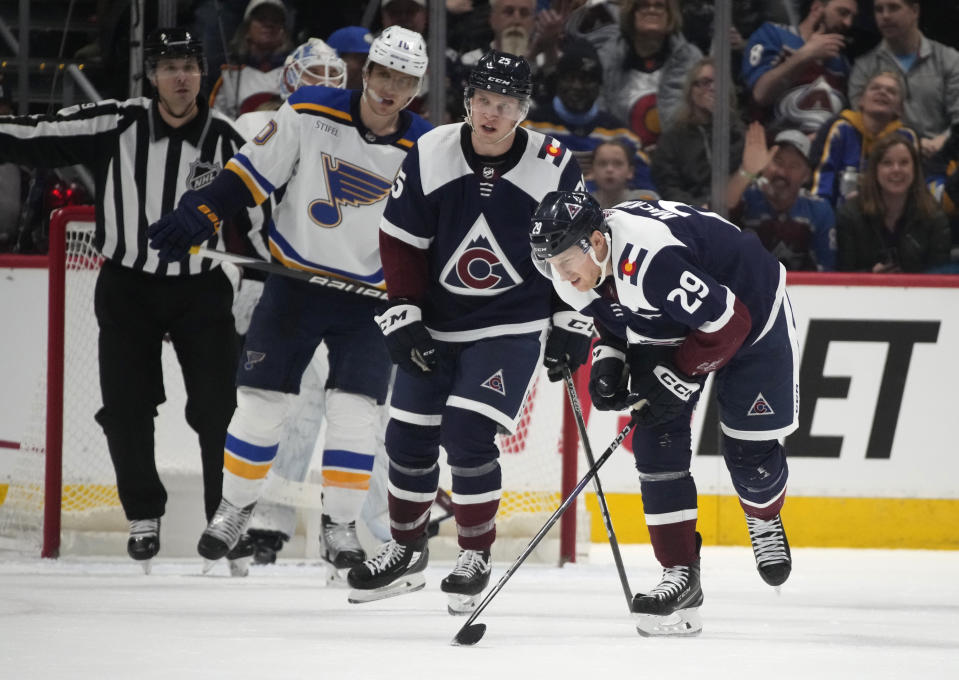 Colorado Avalanche center Nathan MacKinnon, front, struggles to skate off the ice after being injured in a scrum for the puck in front of the net as right wing Logan O'Connor, center, and St. Louis Blues center Brayden Schenn look on in the third period of an NHL hockey game Saturday, Jan. 28, 2023, in Denver. (AP Photo/David Zalubowski)