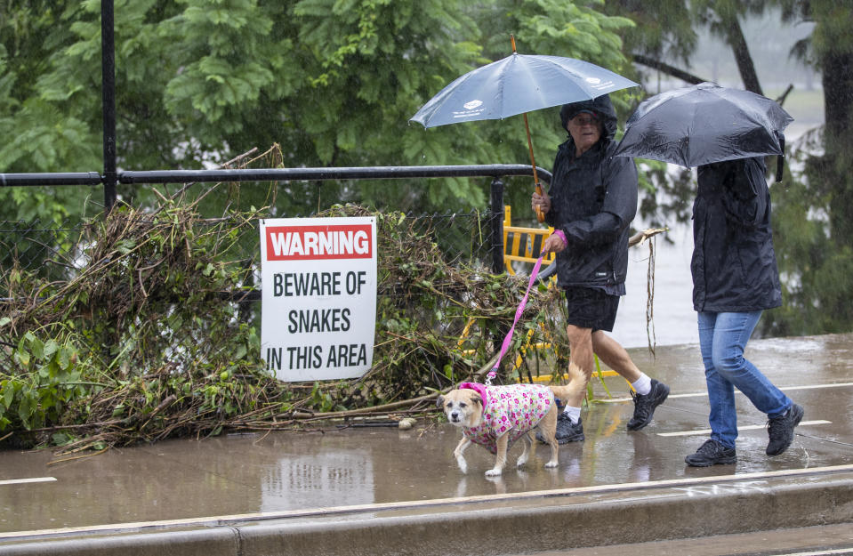 A couple walk along the flooded banks of the Nepean River at Jamisontown on the outskirts of Sydney, Australia, Tuesday, March 23, 2021. Hundreds of people have been rescued from floodwaters that have isolated dozens of towns in Australia's most populous state of New South Wales and forced thousands to evacuate their homes as record rain continues to inundate the countries east coast. (AP Photo/Mark Baker)